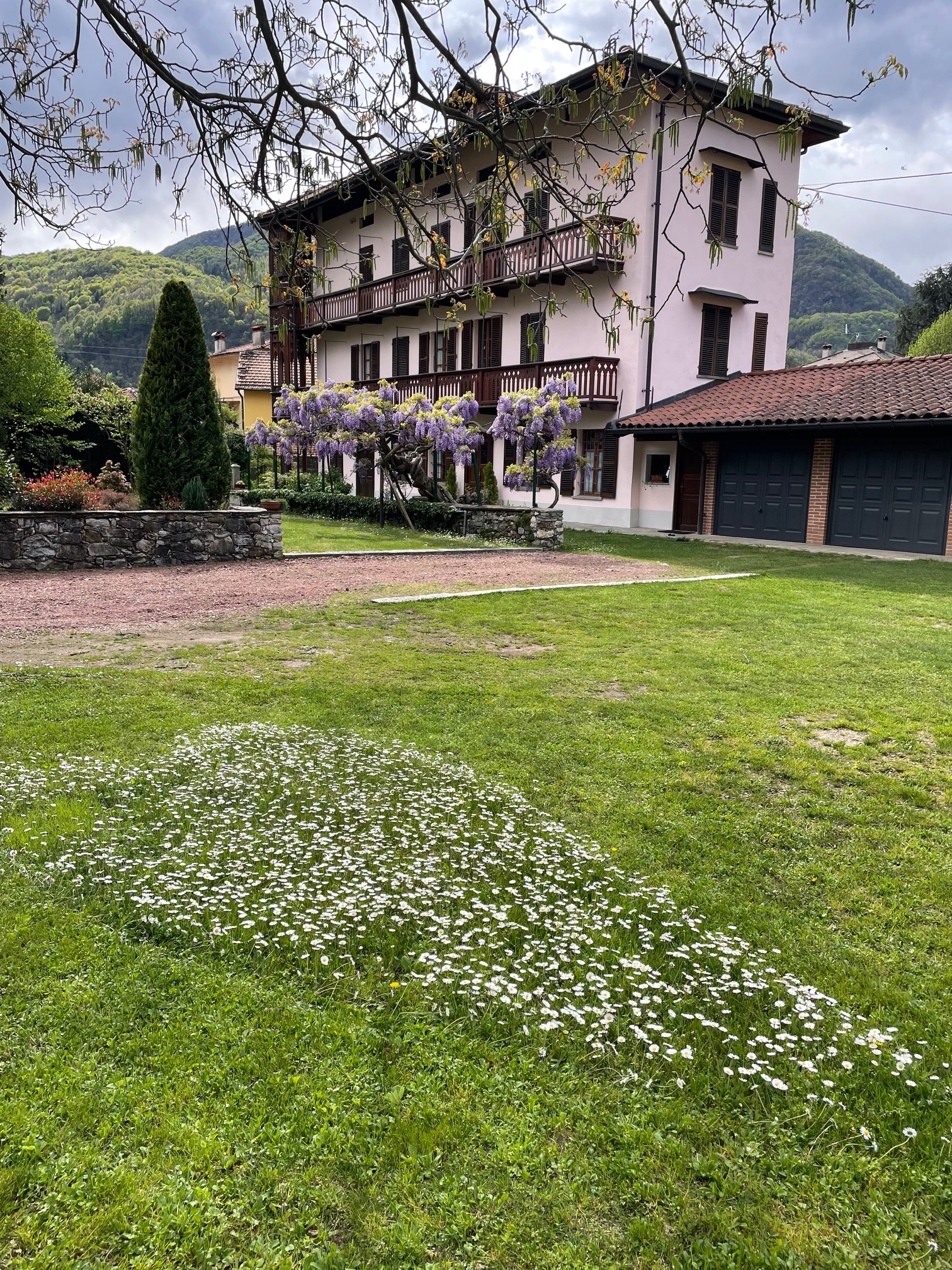 Vista panoramica della dimora con giardino fiorito e sfondo montano
