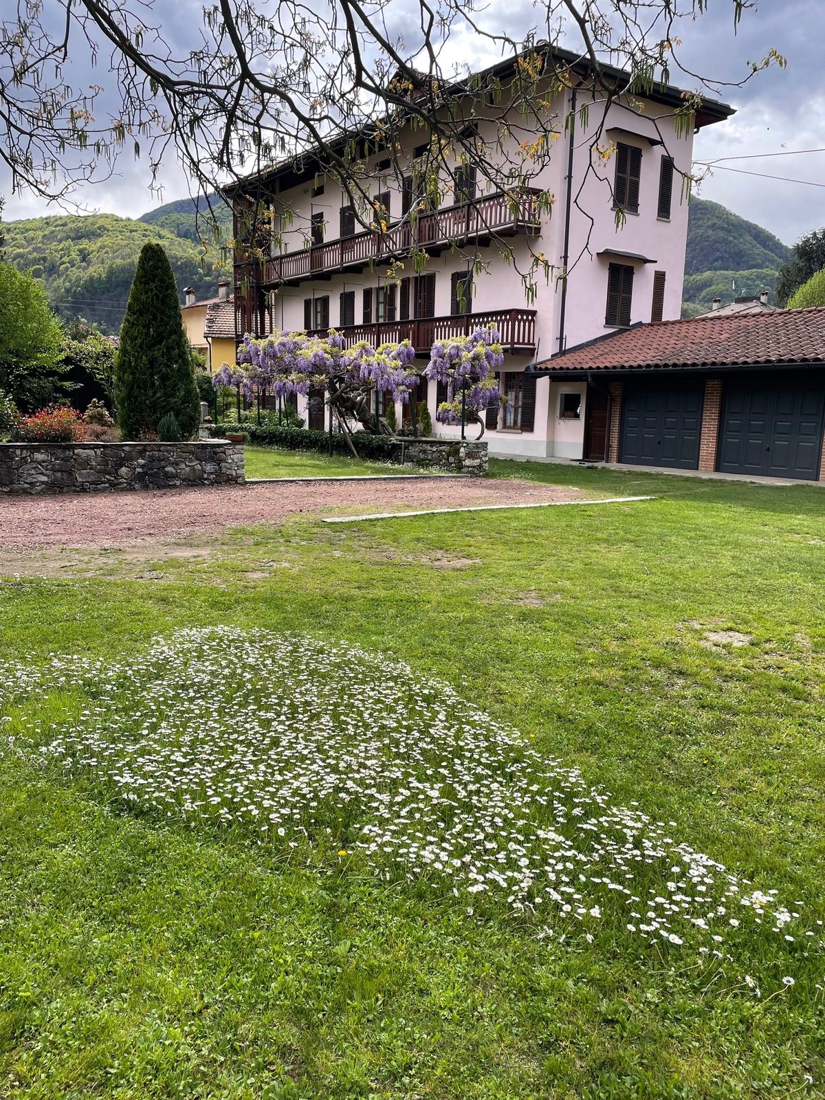 Vista panoramica della dimora con giardino fiorito e sfondo montano